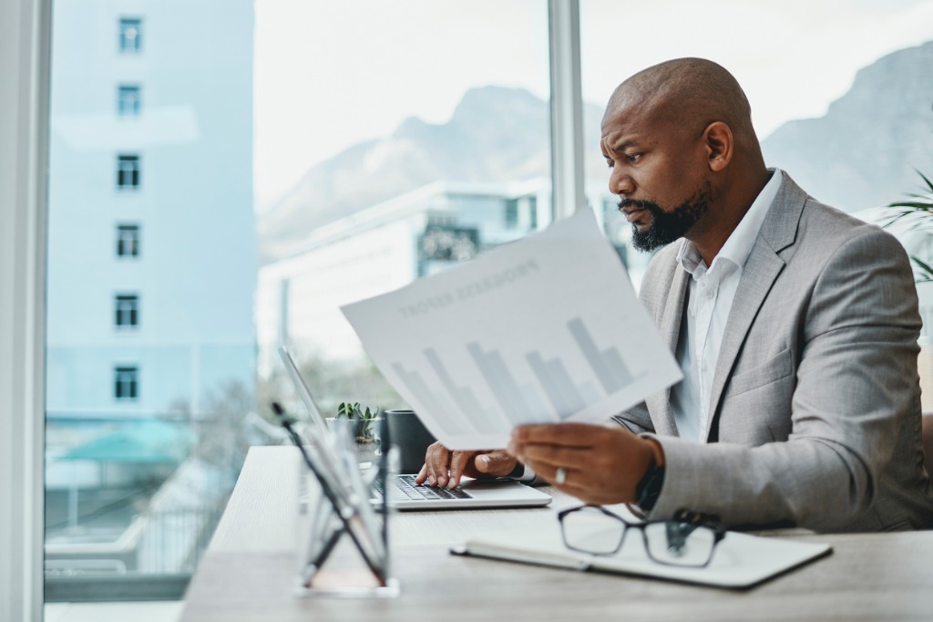 Shot of a mature businessman using a laptop and going over paperwork picture id1355030290