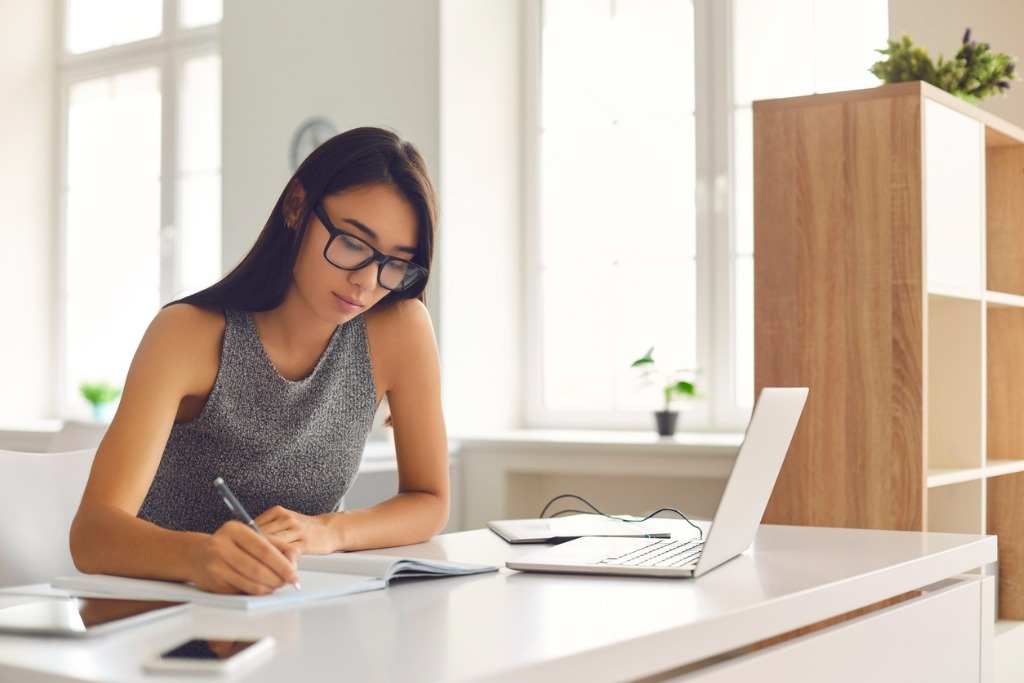 Student in glasses taking notes while watching webinar or listening picture id1282548044